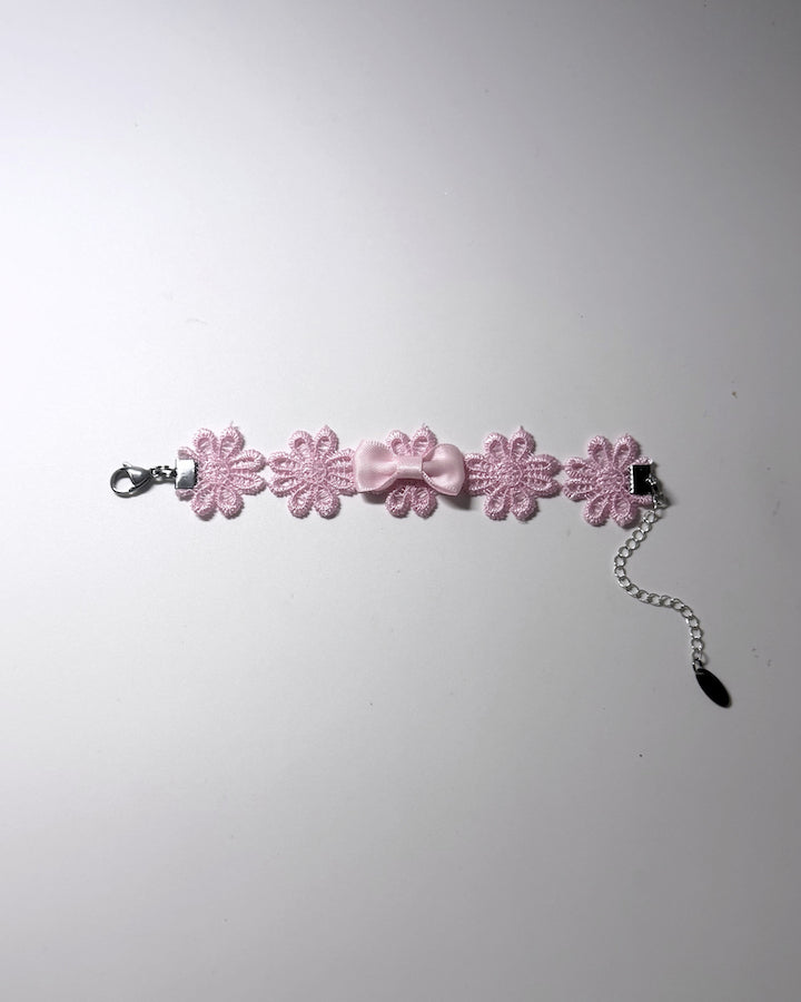 Pink Flower Bow Bracelet on softly lit background laid flat showing the stainless steel extender chain