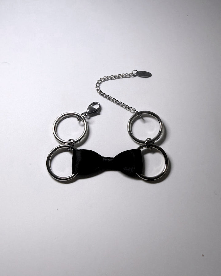 Black Bow Bracelet with Stainless Steel Loops on a softly lit background