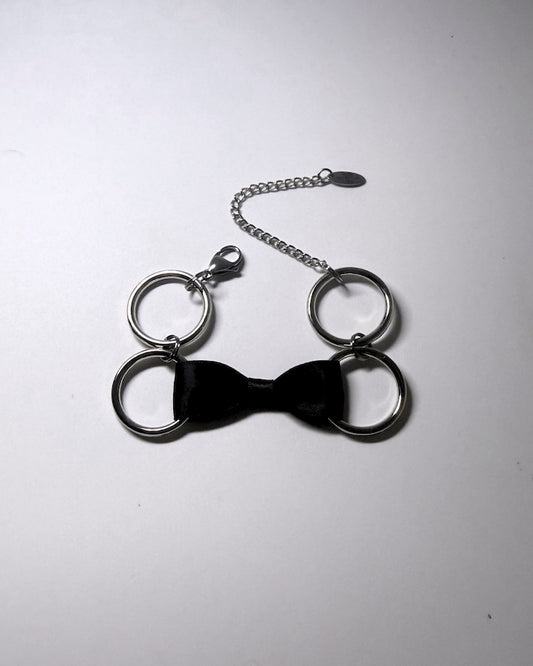 Black Bow Bracelet with Stainless Steel Loops on a softly lit background