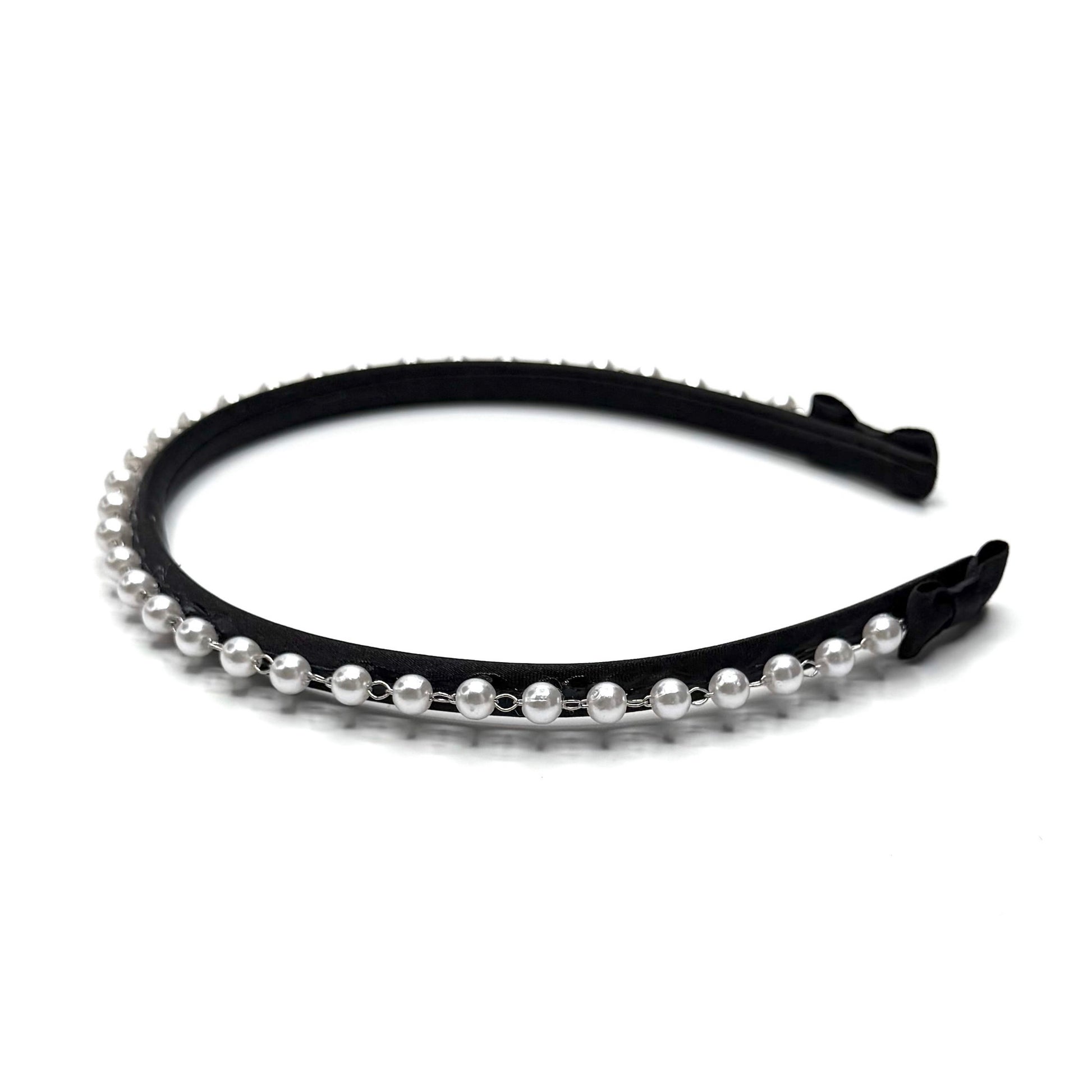 Side view of black headband with pearl strand and black bows