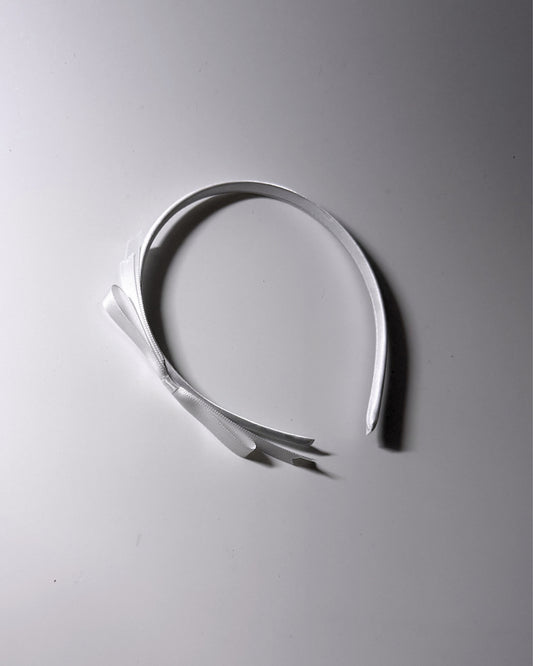 Enchantress White Bow Headband on white background with pretty light