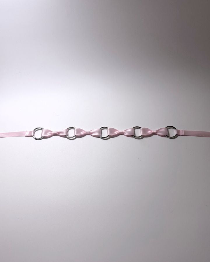 Pink Bow Headband with Silver O Rings and long satin ties laid flat on softly lit surface