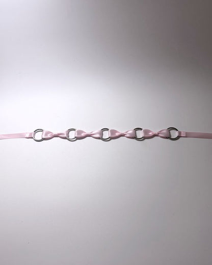 Pink Bow Headband with Silver O Rings and long satin ties laid flat on softly lit surface