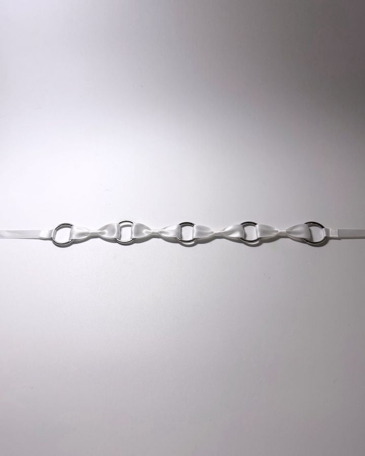 White Bow Headband with Silver O Rings laid flat on softly lit surface