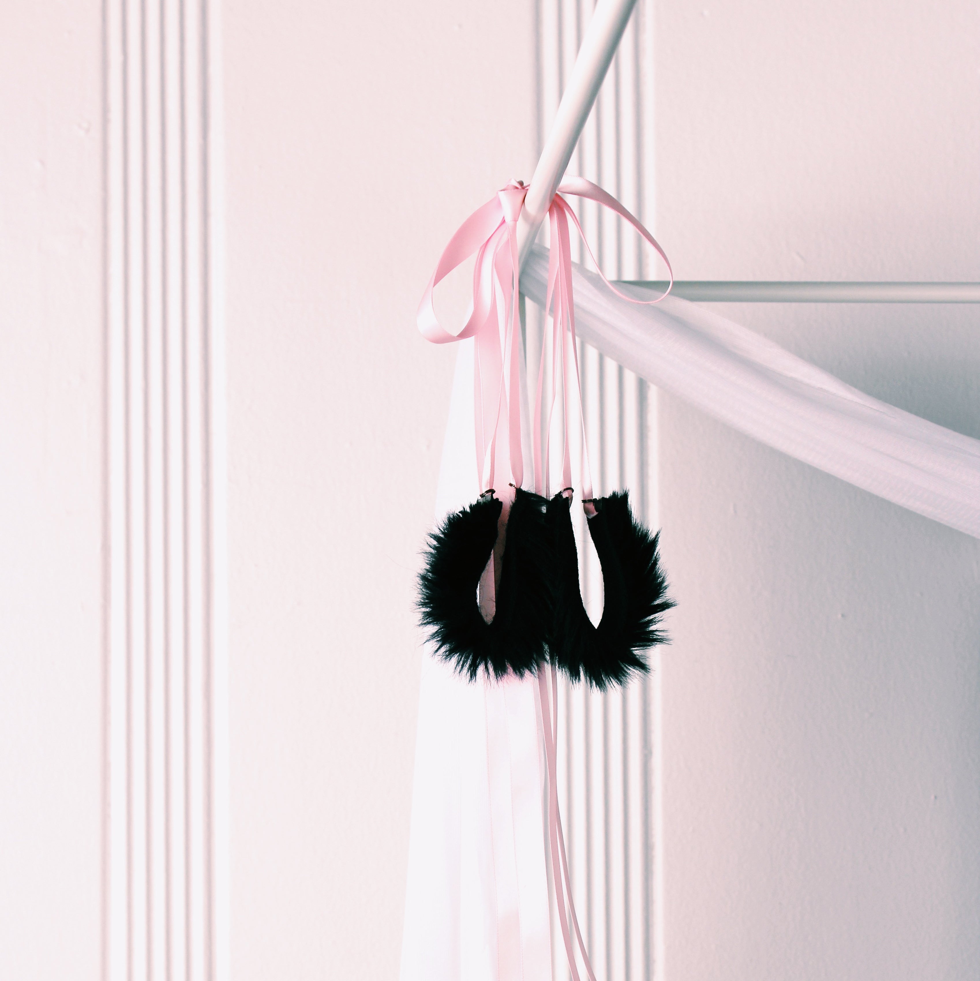 Black Faux Fur Handcuffs with Long Pink Satin Tyes on Bed