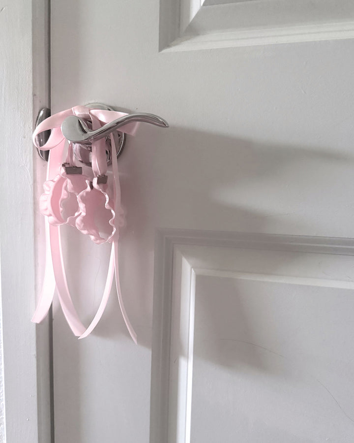 Maiden Pink Ruffled Handcuffs on softly lit surface on doorknob
