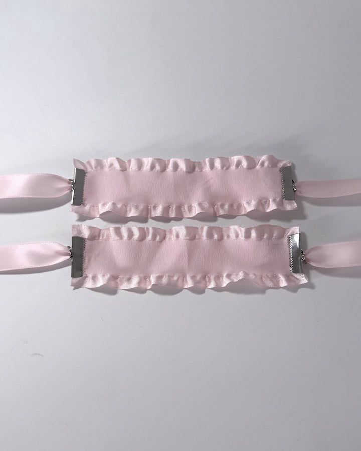 Maiden Pink Ruffled Handcuffs on softly lit surface flatlay view