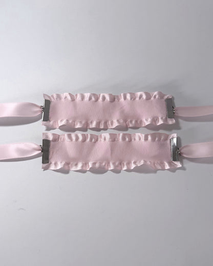 Maiden Pink Ruffled Handcuffs on softly lit surface flatlay view