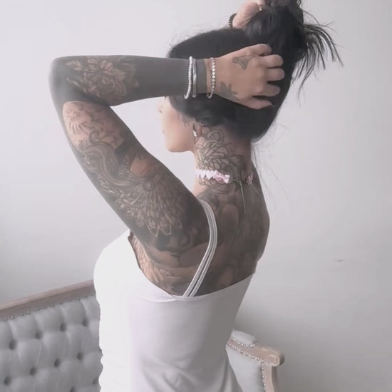 brunette model in pink heart bow choker wearing white dress and covered in tattoos
