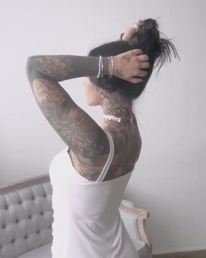 brunette model in pink heart bow choker wearing white dress and covered in tattoos