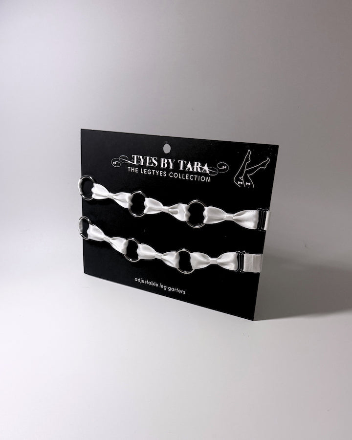 White Bow Leg Garters with stainless steel o rings displayed on black retail card