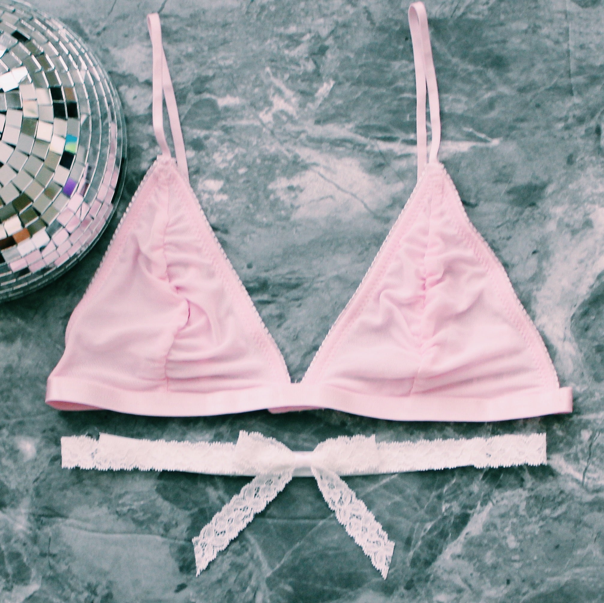white lace bow belt with pink bra on gray marble