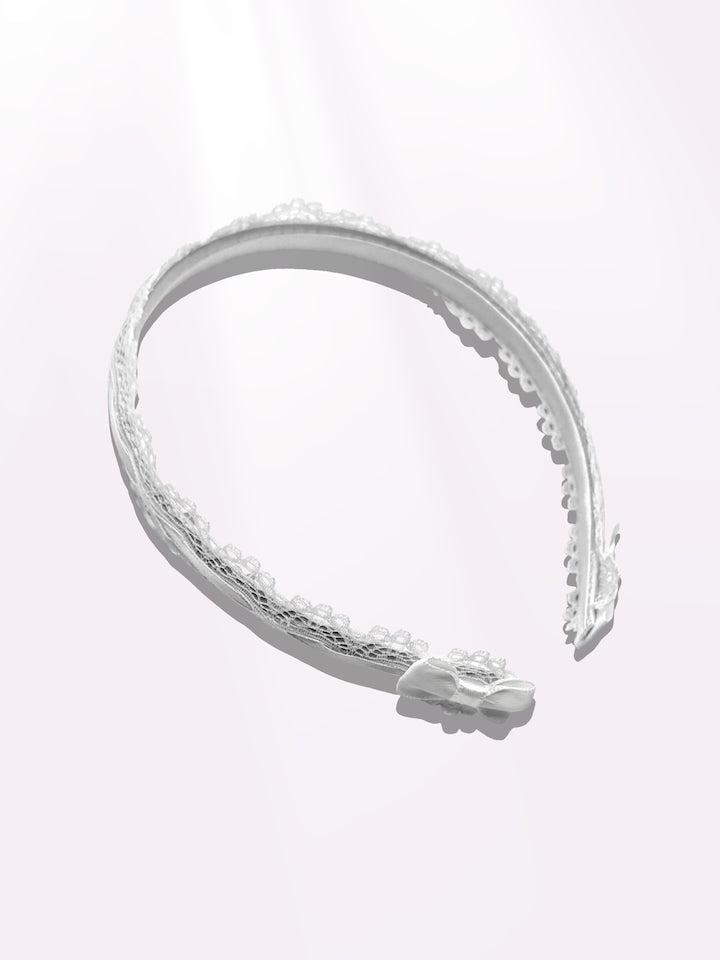 white lace bow headband on light pink background